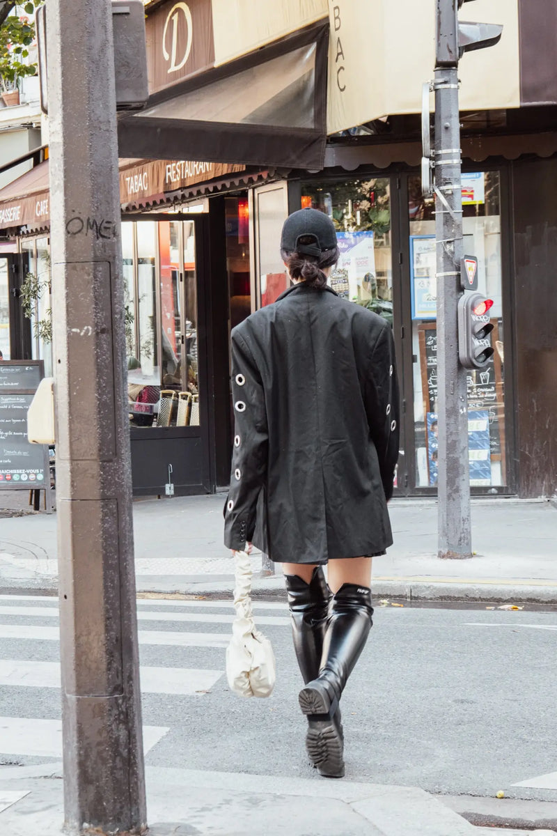 Femme portant PIMP UP™ BASIC BLACK avec des bottes noires dans une rue parisienne